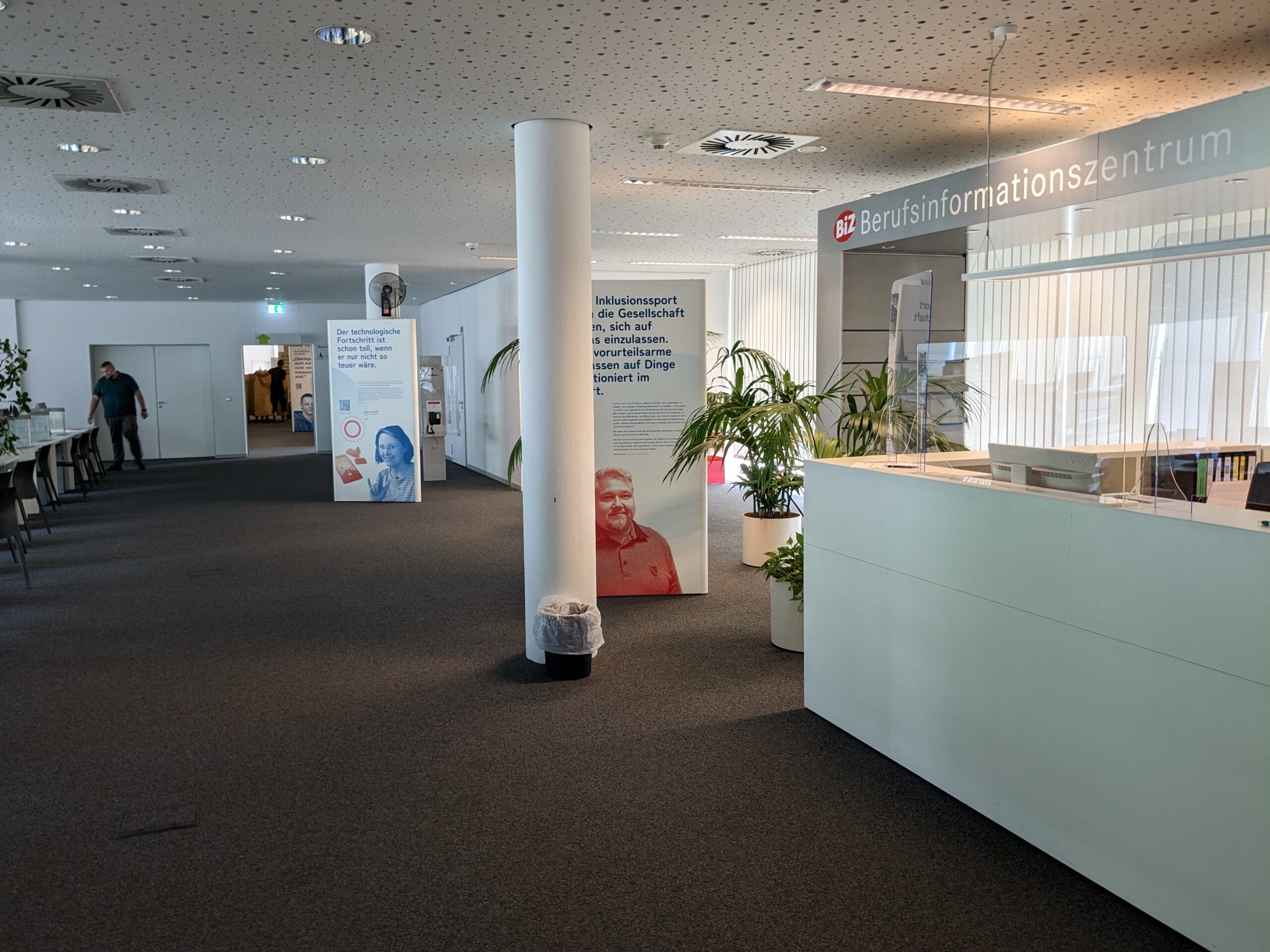 Nach der Eröffnungsveranstaltung schauen sich die Besucher die Ausstellung an, auf dem Bild betrachten die Gäste die grüne Wand, die mit Kunstplfanzen dekoriert ist