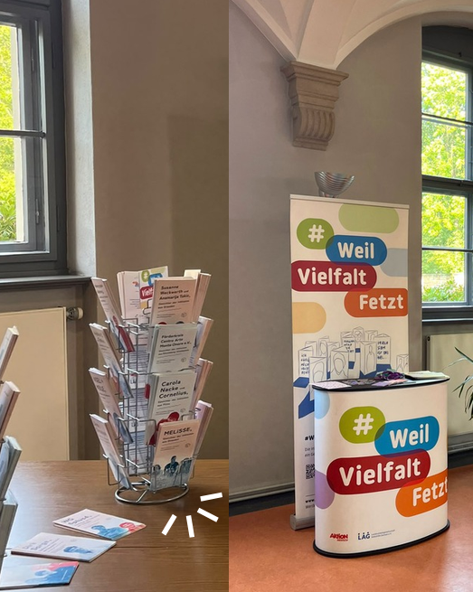 Flyer mit den Portraits der "Gesicher der Inklusion" stecken in einem Flyerständer, daneben ein Rollup mit dem Logo #WeilVielfaltFetz